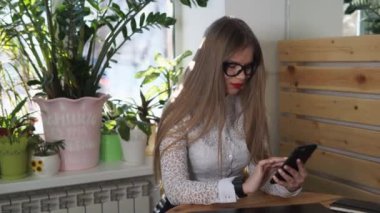 Güzel bir Yöneticisi bir akıllı telefon üzerinde bir arkadaşıyla öğle yemeği molası sırasında yeniden yazar