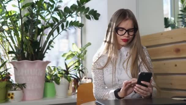 Geschäftsfrau checkt Weltnachrichten auf ihrem Handy, auf ihrer Hand eine intelligente Uhr — Stockvideo