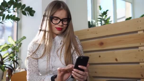 Mujer de negocios está viendo noticias en su teléfono inteligente durante la pausa para el almuerzo — Vídeos de Stock