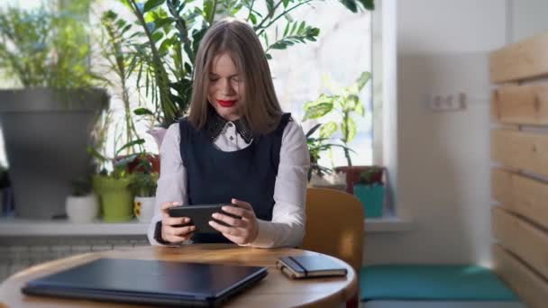 Young woman watches news on smartphone for the development of her business — Stock Video