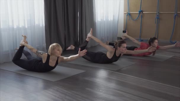 Unga kvinnor lära sig asanas från yoga för att bli mer flexibla och plast — Stockvideo