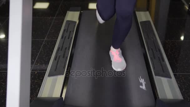 Close up shot of the treadmill on which the girl is actively running — Stock Video