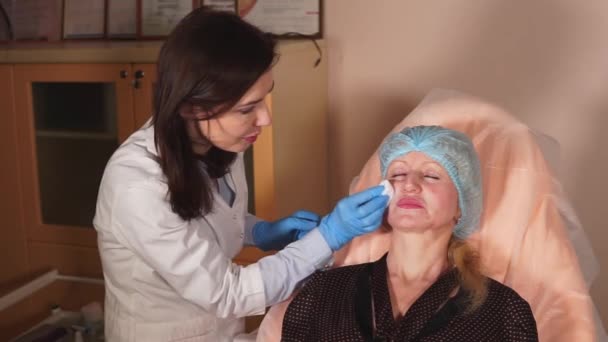 Médecin nettoie la peau du visage pour une femme qui est venue faire des procédures anti-âge — Video