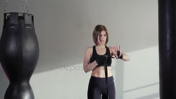 Young athlete puts on elastic bandages for exercising on hands — Stock Video