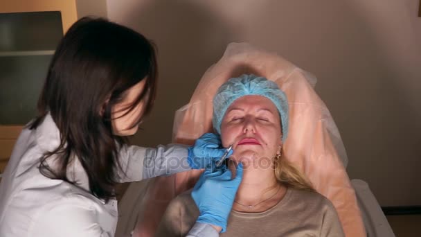 Пластический хирург делает укол для взрослой женщины в области носогубных складок — стоковое видео
