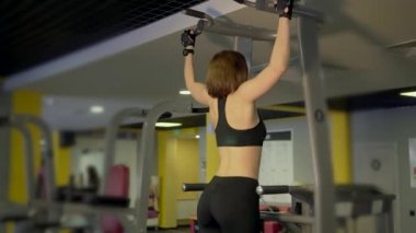Fitness için gelen kadın kaslarını güçlendirmek için simülatör üzerinde yukarı çeker.