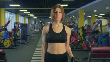 Sportif bir kadın bir dumbbell pazı pompa için bir fitness merkezinde asansörleri.
