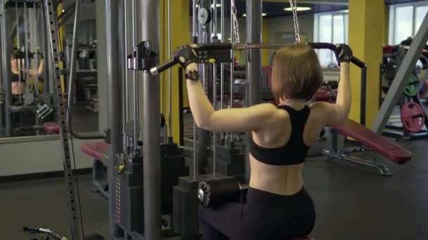 Спортивная женщина занимается физическими упражнениями на тренажере Hammers . — стоковое видео