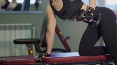 Spor hocası bir Spor Kulübü'nün bir dumbbell ile sırt kasları sallıyor.