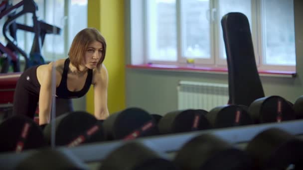 Uma mulher esportiva usa halteres para aumentar o complexo de tríceps e ombros . — Vídeo de Stock