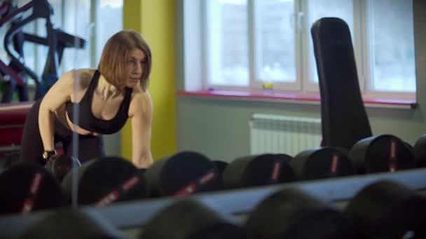 Una mujer deportiva usa pesas para aumentar el complejo de tríceps y hombros . — Vídeos de Stock