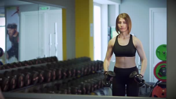 Keskin hareketleri ile bir kadın kollarını yukarıya için spor yapıyor dumbbells ile yükseltir.. — Stok video