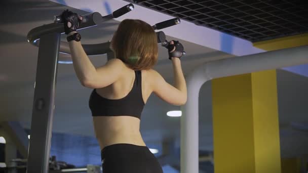 Uma mulher de esportes faz puxando todo o corpo nas vigas cruzadas no clube de esportes . — Vídeo de Stock