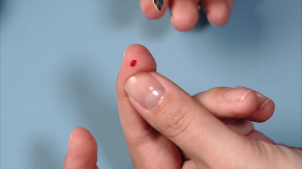 Feche a amostra de sangue para o glicosímetro na tira de teste. Mão feminina — Vídeo de Stock