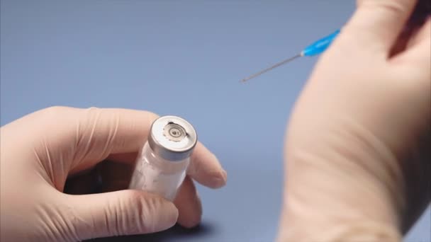 Doctor perforando la tapa de la ampolla con jeringa — Vídeo de stock