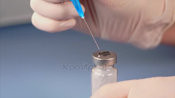 Doctor perforando la tapa de la ampolla con jeringa — Vídeo de stock