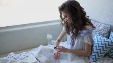 Genç kadın yatak odasında akıllı saatler hakkında gelen postaları denetler.