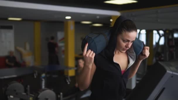 Die Sportlerin geht mit einer Last auf den Schultern einen sportlichen Schritt auf dem Laufband. — Stockvideo