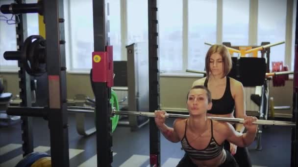 Donna è impegnata in un fitness club con un istruttore per aumentare la massa muscolare . — Video Stock