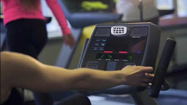 Μια γυναίκα επιλέγει ένα πρόγραμμα σε ένα τρέξιμο προσομοιωτή για την αλλαγή των ασκήσεων. — Αρχείο Βίντεο
