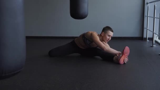 Young athlete stretches the muscles of the legs and back after exercising. — Stock Video