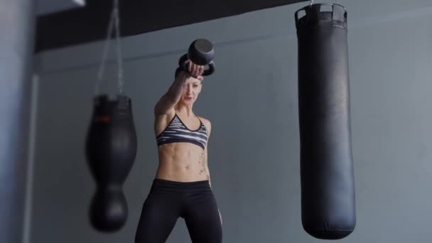 Een vrouw van de sport doen sit-ups met gewichten te verhogen spiermassa van handen. — Stockvideo