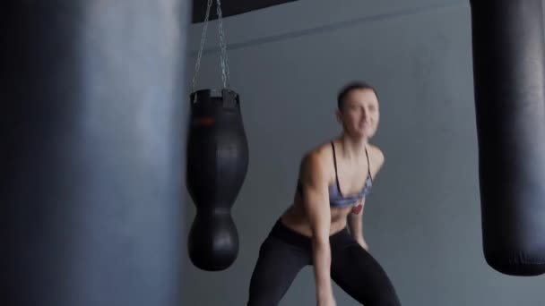 Una mujer con un almacén de cuerpo atlético está comprometida con un simulador muscular . — Vídeo de stock