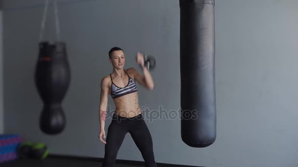 A woman with developed muscular muscles is engaged in a gym with projectile — Stock Video