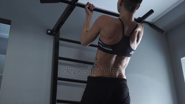 Uma mulher esportiva puxa um simulador para melhorar o tríceps e o bíceps . — Vídeo de Stock