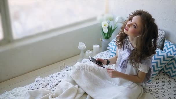 Jeune femme profiter de la matinée au lit et écouter de la musique au téléphone . — Video