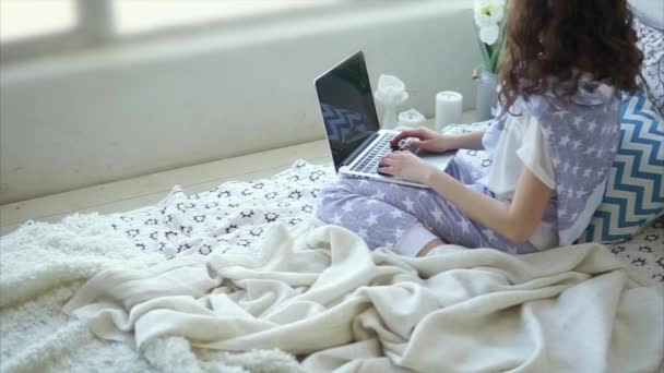 젊은 여자는 침실에서 노트북에 메시지를 씁니다.. — 비디오