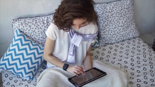 Pretty woman using tablet computer online shopping at home sitting on bed. — Stock Video