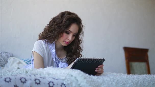 Νεαρή γυναίκα μιλώντας με φίλους χρησιμοποιώντας tablet ξαπλωμένοι στο κρεβάτι στην κρεβατοκάμαρα. — Αρχείο Βίντεο