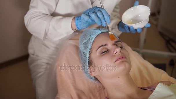 Косметолог надевает маску для лица на пациентку. Омоложение косметологии — стоковое видео