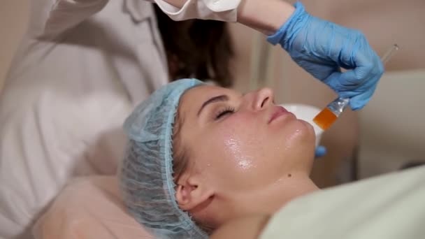 Una mujer en un spa recibiendo máscara facial. Salón de belleza. Rejuvenecer la cosmetología . — Vídeos de Stock