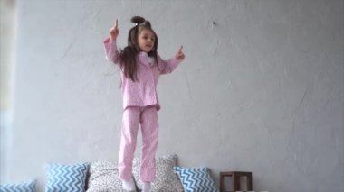 Mutlu genç kız yatak odasında eğleniyor. Atlama ve yatağa oynama.