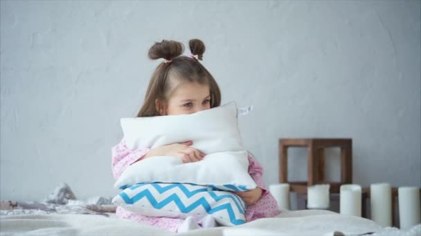 Una niña en pijama hecho en casa pone las almohadas, se divierte . — Vídeos de Stock