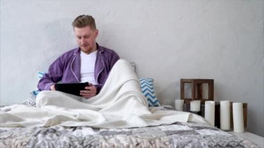 Ev giysileri ciddi bir adam iş bir tablet üzerinde çalışmaktadır.