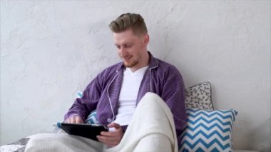 Erkek müşteri online alışveriş. Adam yatakta oturmuş tablet ile.