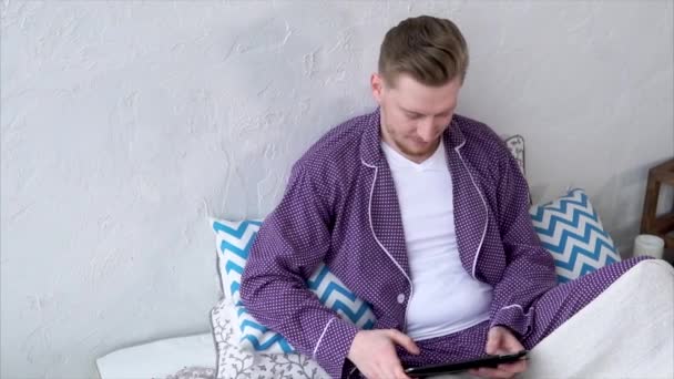 Mann mit Tablet im Chat mit Freunden in sozialen Netzwerken. Männchen im Pyjama. — Stockvideo