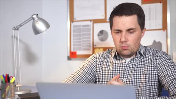 Egy koncentrált, aki egy irodában dolgozik próbálják eldönteni, egy laptop — Stock videók