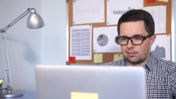 Primer plano de una cara de hombre que trabaja con el ordenador portátil en la oficina — Vídeos de Stock