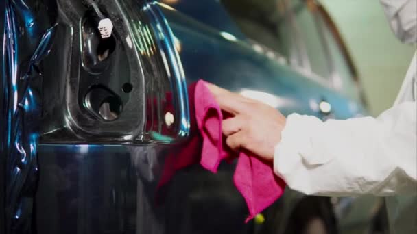 Эксперт на станции техобслуживания очищает автомобиль тряпкой после нанесения виниловой пленки — стоковое видео