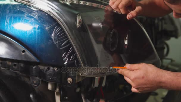 Primer plano de las manos cortando la película de vinilo en los faros del coche . — Vídeos de Stock