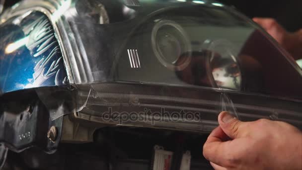 Close-up shot van de scheur van de handen uit de film van de vinyl op de koplampen van de auto. — Stockvideo