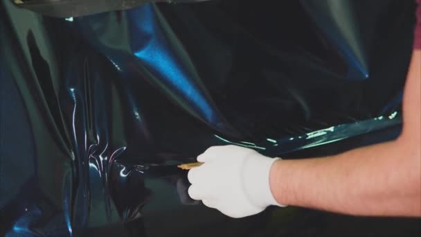 Worker at the service station smoothing vinyl film by construction hair dryer. — Stock Video