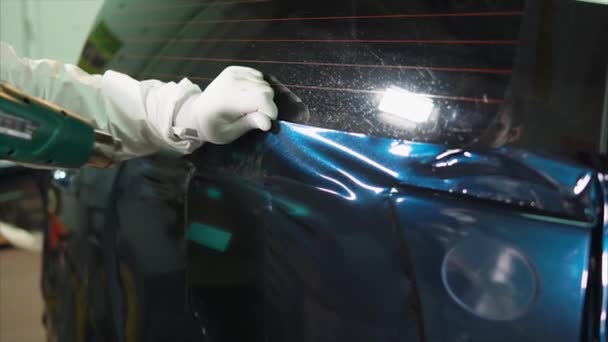 Werknemer garage verwarmt haardroger continu oppervlak vinyl film. — Stockvideo
