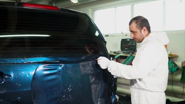 Un experto en el taller de carrocería aplica superficie de vinilo al vehículo . — Vídeos de Stock