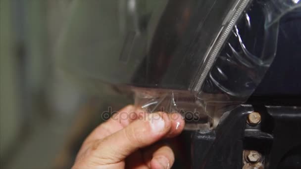 Gros plan des mains arracher le film vinyle sur les phares de la voiture . — Video