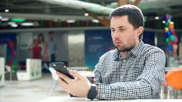 Hombre usando teléfono inteligente y tomando café en el centro comercial — Vídeos de Stock